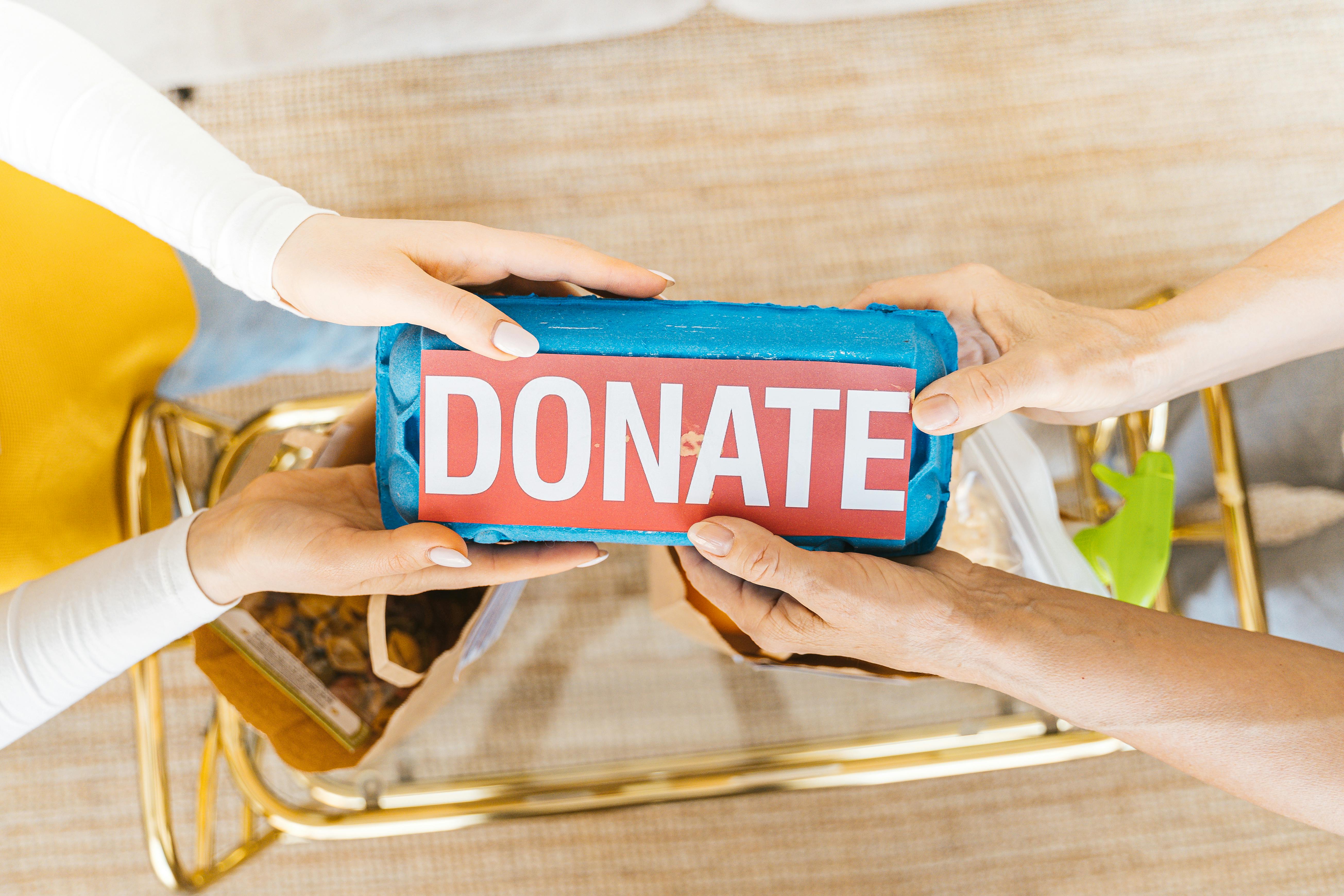 Hands holding a donation box above a table with bags and supplies